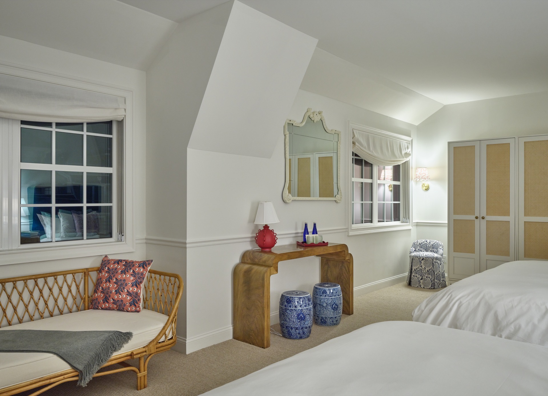 A wide view of a hotel room with a bed, window, sofa, desk, and mirror.